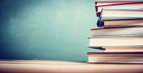 Textbooks on wooden school desk with chalkboard