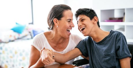 Disabled Latino teenager with Celebral Palsy and mother laughing