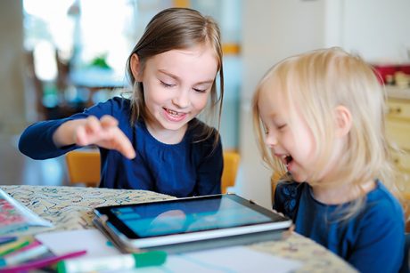 Two little sisters playing with a digital tablet